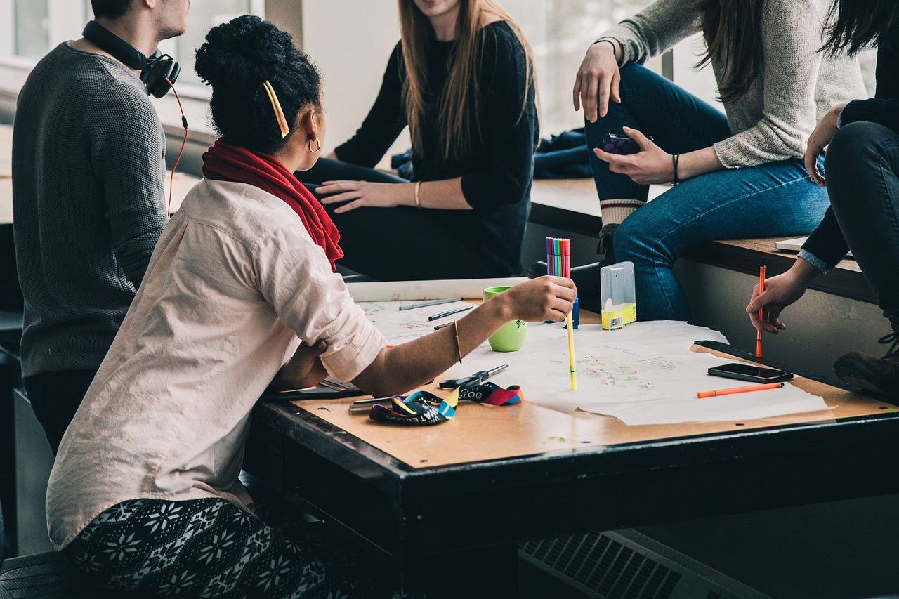 Stock image of people meeting around a table and paper, no faces shown